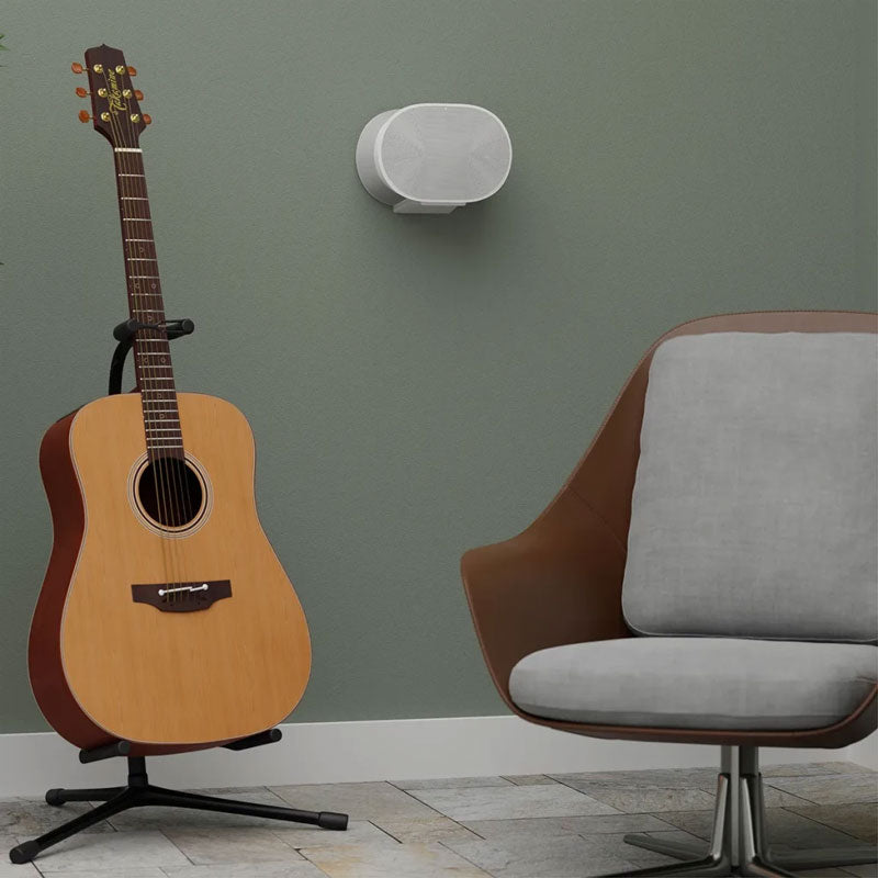 Sanus Fixed Speaker Wall Mount WSFME31-W2, white speaker wall-mounted beside a chair and guitar